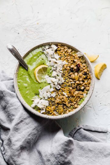 green smoothie in a bowl with granola and lemon toppings