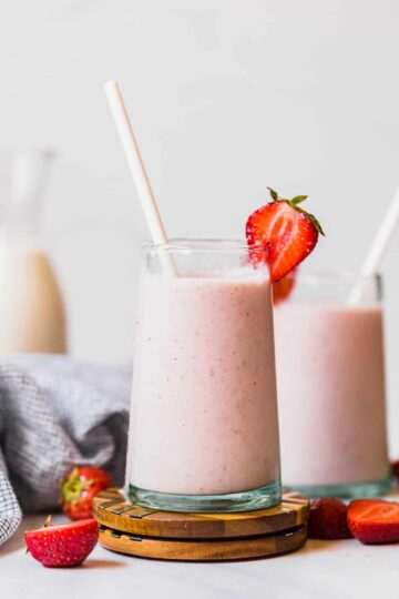 strawberry banana smoothie in a glass cup with a straw